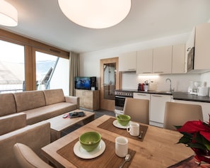 Una habitación de hotel moderna con sala de estar, kitchenette y un ventanal con vistas.