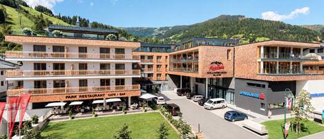 A hotel with multiple floors, outdoor seating, and a view of the surrounding hills.
