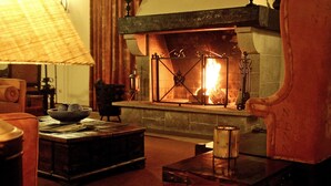 Una sala de estar acogedora con una chimenea de piedra, una mesa de centro de madera y un sillón cómodo.