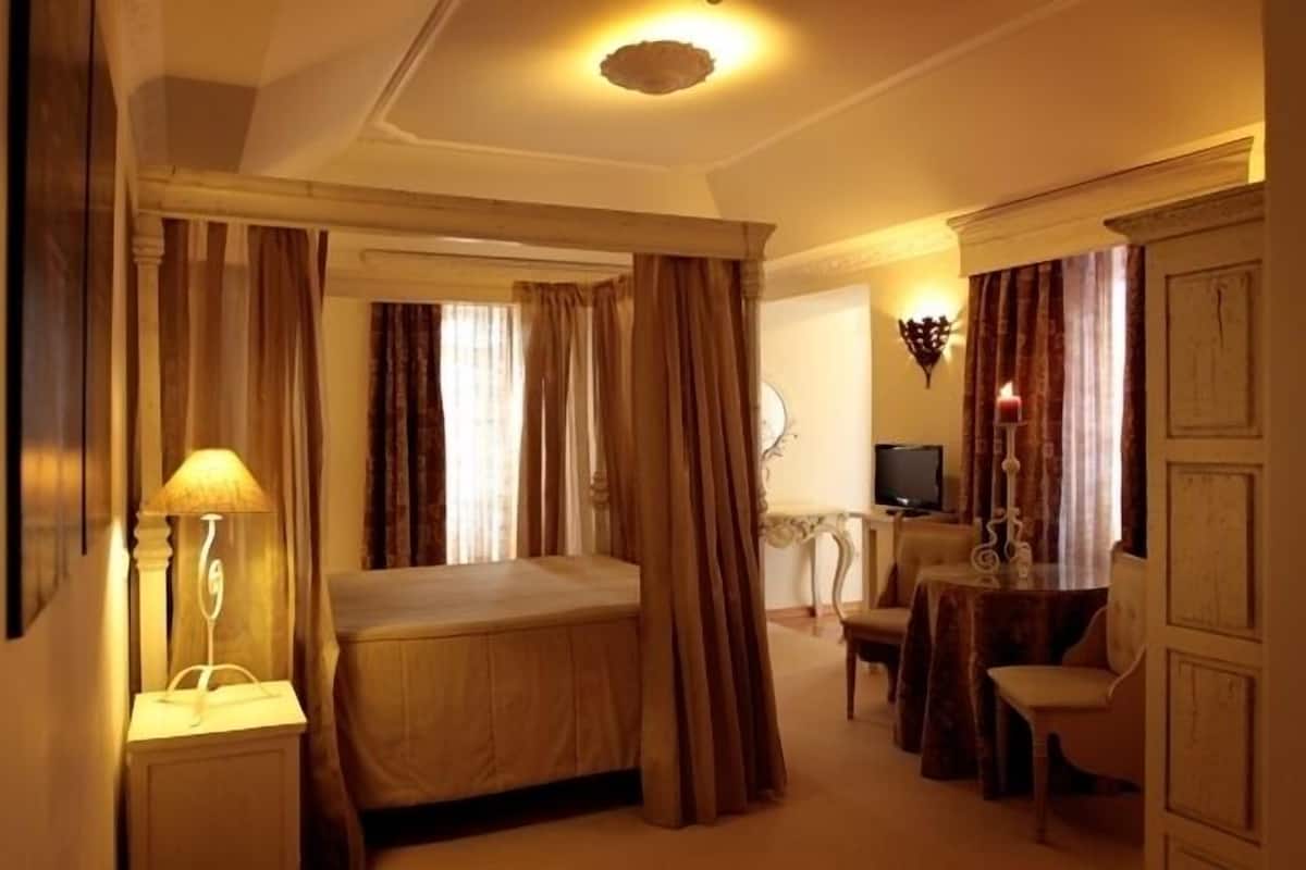 A hotel room with a bed, a desk, a chair, a television, and a lamp.