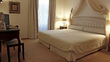 A bedroom with a large bed, a desk with a lamp, and curtains.