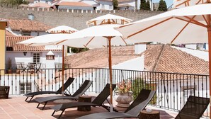 Una terraza con tumbonas y sombrillas, con vistas a un pueblo de edificios históricos.
