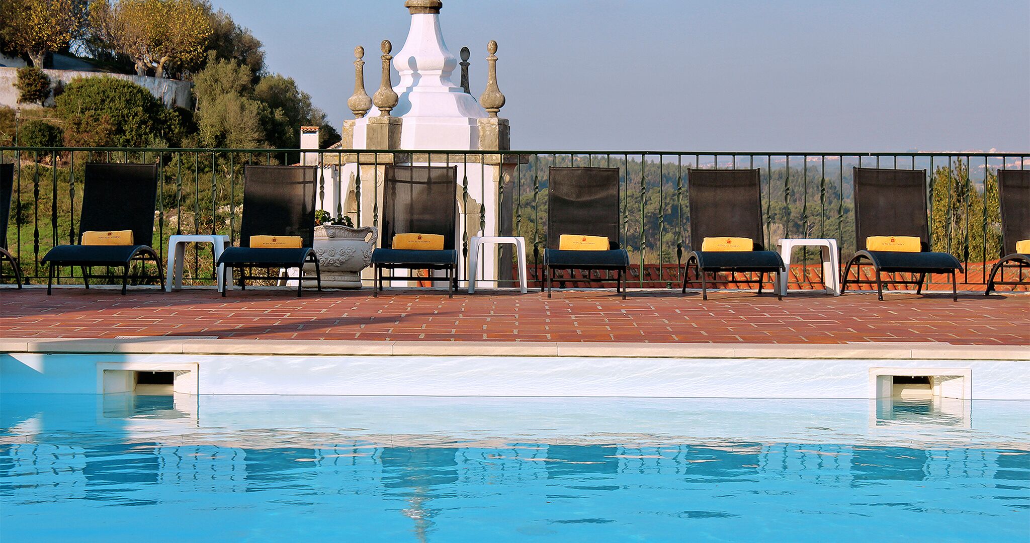 A pool area with lounge chairs and a white building in the background.