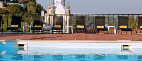 A pool area with lounge chairs and a white building in the background.