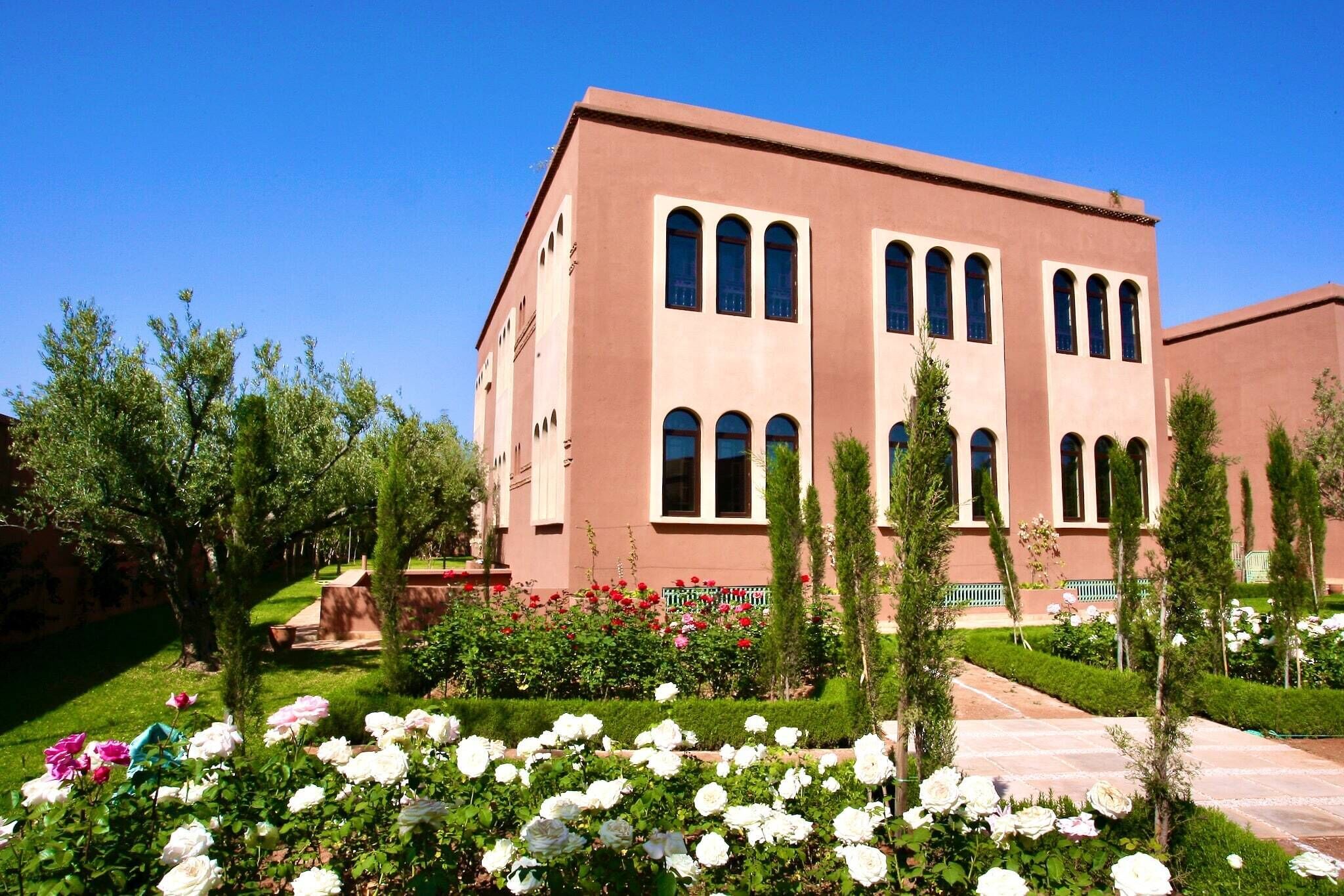 A building with a symmetrical facade, multiple windows, and a well-maintained garden with various plants and flowers.