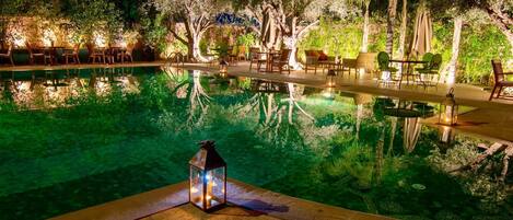 Una piscina al aire libre, sombrillas, sillones reclinables de piscina