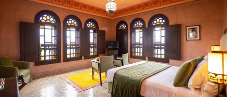 Une chambre d’hôtel avec un lit, un bureau, une chaise et un téléviseur.