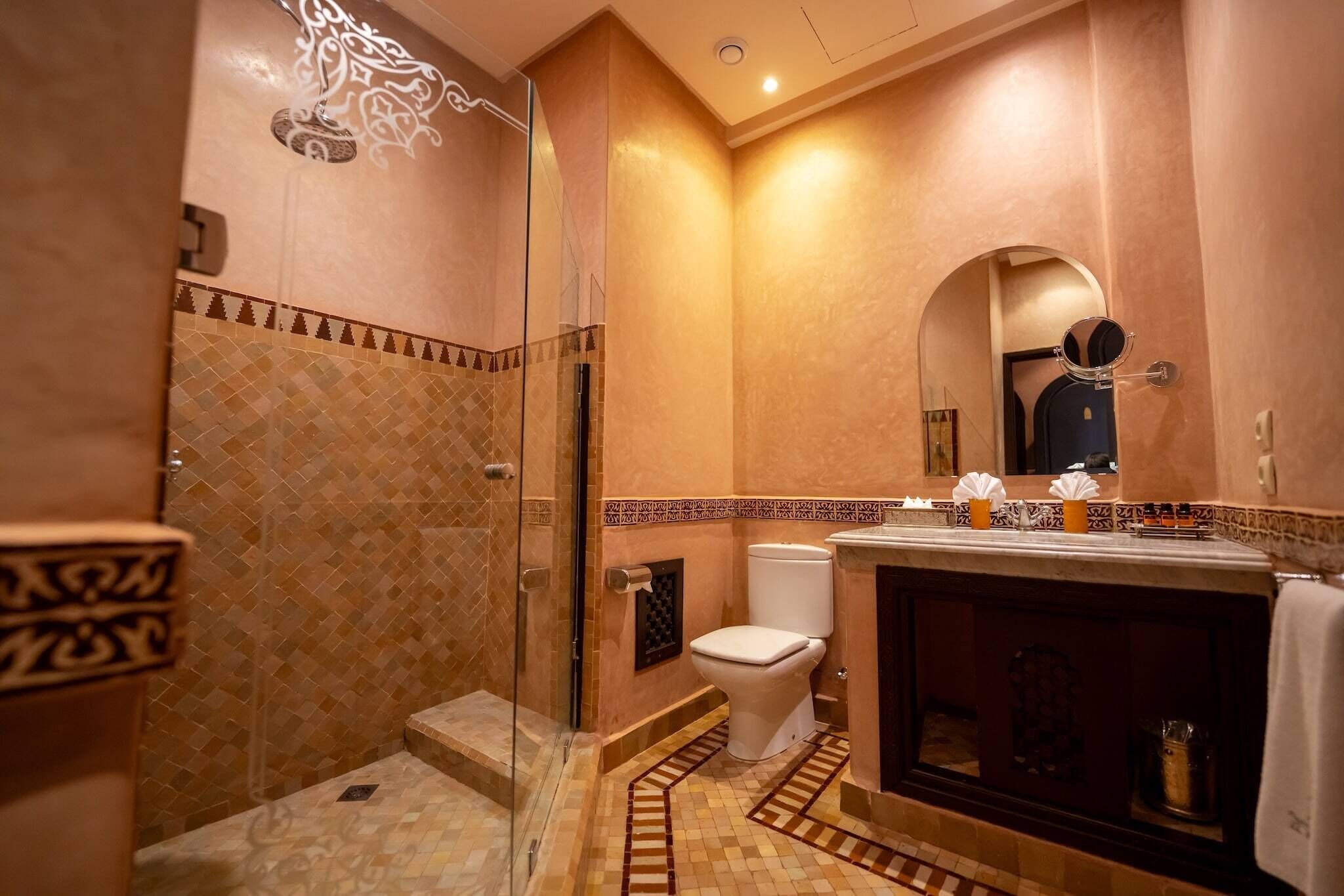 A bathroom with a glass-enclosed shower, a toilet, and a vanity with a mirror.