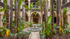 A courtyard with a central fountain, surrounded by tall palm trees and arches. - Al Fassia Aguedal (Marrakech)