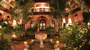 A courtyard with a central fountain, surrounded by lush greenery and a tiled floor. - Al Fassia Aguedal (Marrakech)