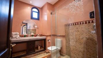 A bathroom with a glass-enclosed shower, a toilet, and a vanity with a mirror and towel rack.