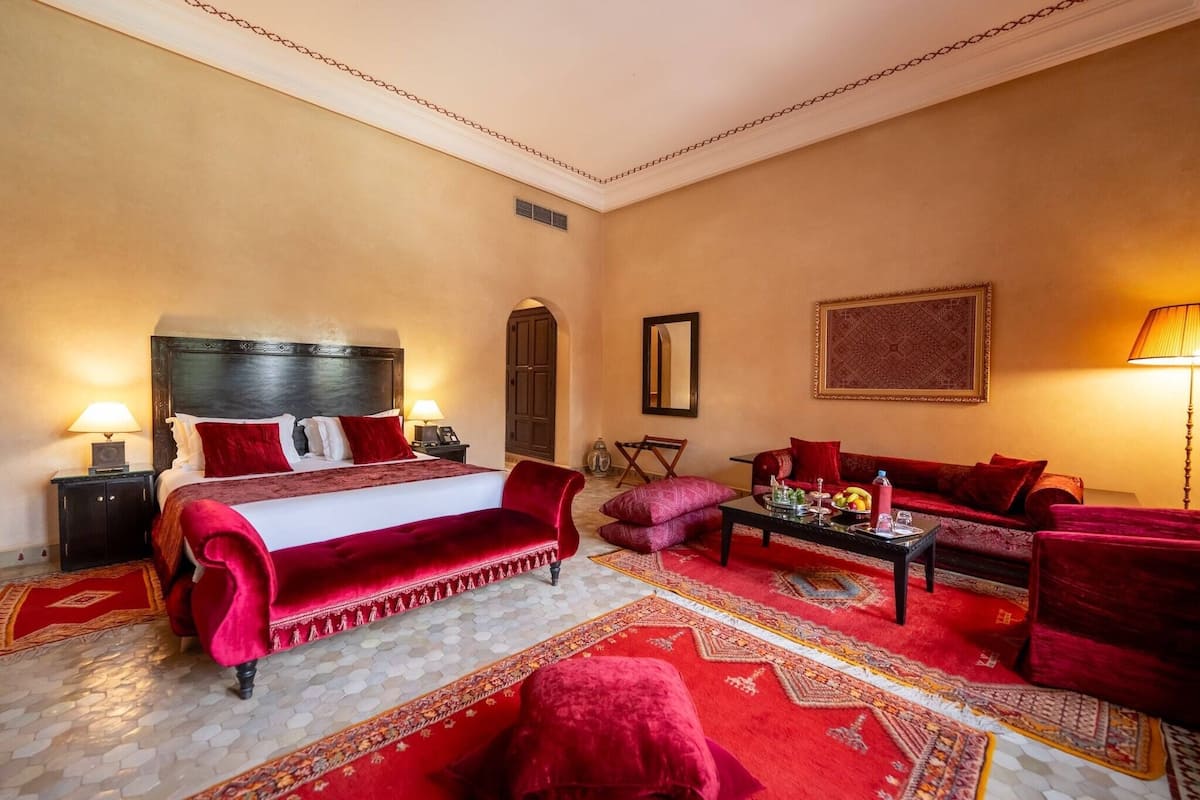 Quarto de hotel com uma cama grande, um sofá, uma mesa de centro e um tapete.