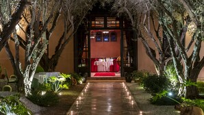 A pathway leading to a building with a red carpet and a table set up outside, surrounded by trees and illuminated lights. - Al Fassia Aguedal (Marrakech)