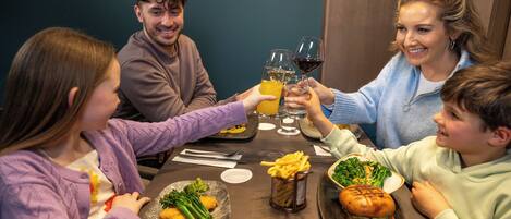 A family dining at a restaurant with a variety of dishes, including burgers and fries, and drinks.