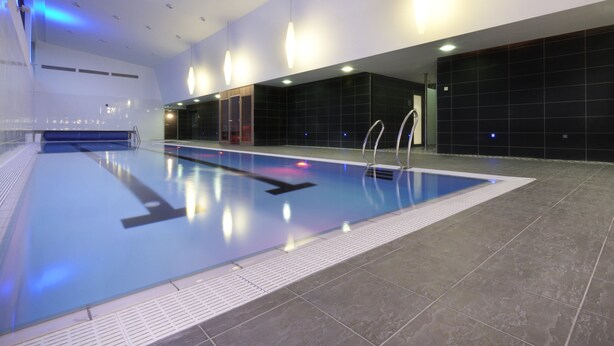 An indoor swimming pool with clear lanes, a tiled floor, and overhead lighting. - Clayton Hotel Galway (Galway)