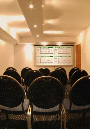 A conference room with rows of chairs facing a screen displaying financial charts. - Dom Casimi (Kraków)