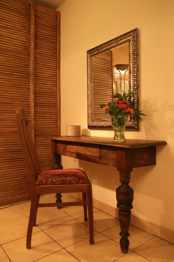 A wooden chair with a cushioned seat, a wooden table with a vase of flowers, and a mirror on the wall. - Dom Casimi (Kraków)