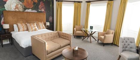 Ein Hotelzimmer mit einem Bett, einer Couch, einem runden Couchtisch und zwei Sesseln.