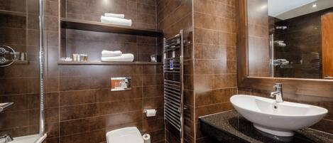 Un baño moderno con un lavamanos grande, un inodoro y una zona de ducha.