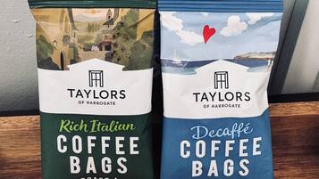Two bags of Taylors Coffee Bags, one labeled 'Rich Italian Roast' and the other 'Decaffeé Roast', alongside a bag of Taylors Potato Crisps.