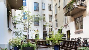 Ein Innenhof mit einem Glastisch, Bänken, Blumentöpfen und Fahrrädern.