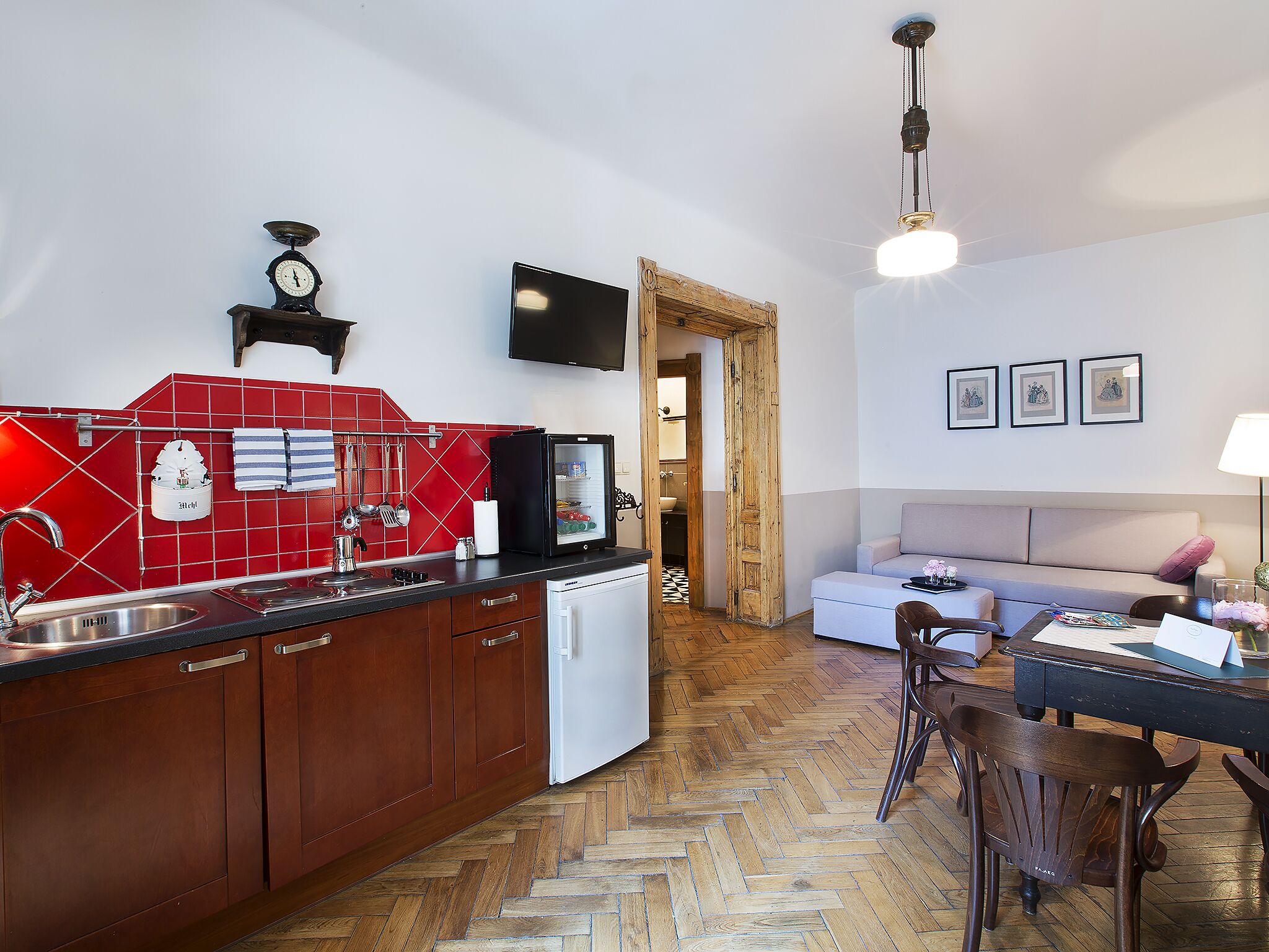 A compact kitchen with a red backsplash, a white refrigerator, and wooden cabinets.