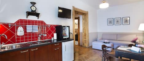 A compact kitchen with a red backsplash, a white refrigerator, and wooden cabinets.