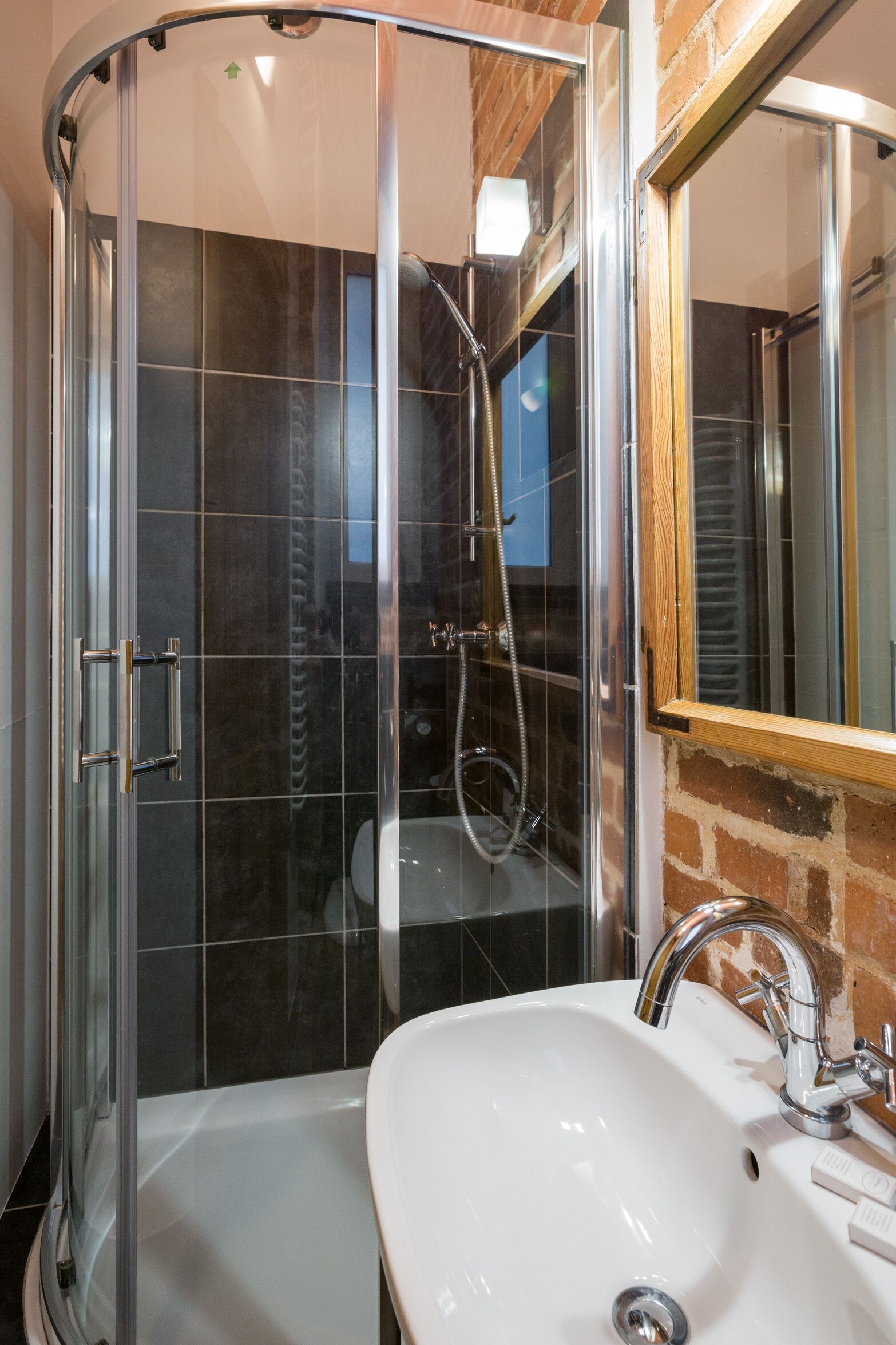A bathroom with a glass-enclosed shower, a white sink, and a mirror.