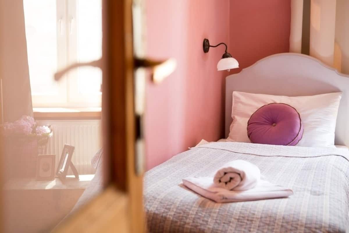 Un dormitorio con cama, lámpara de noche, ventana y vistas al exterior.