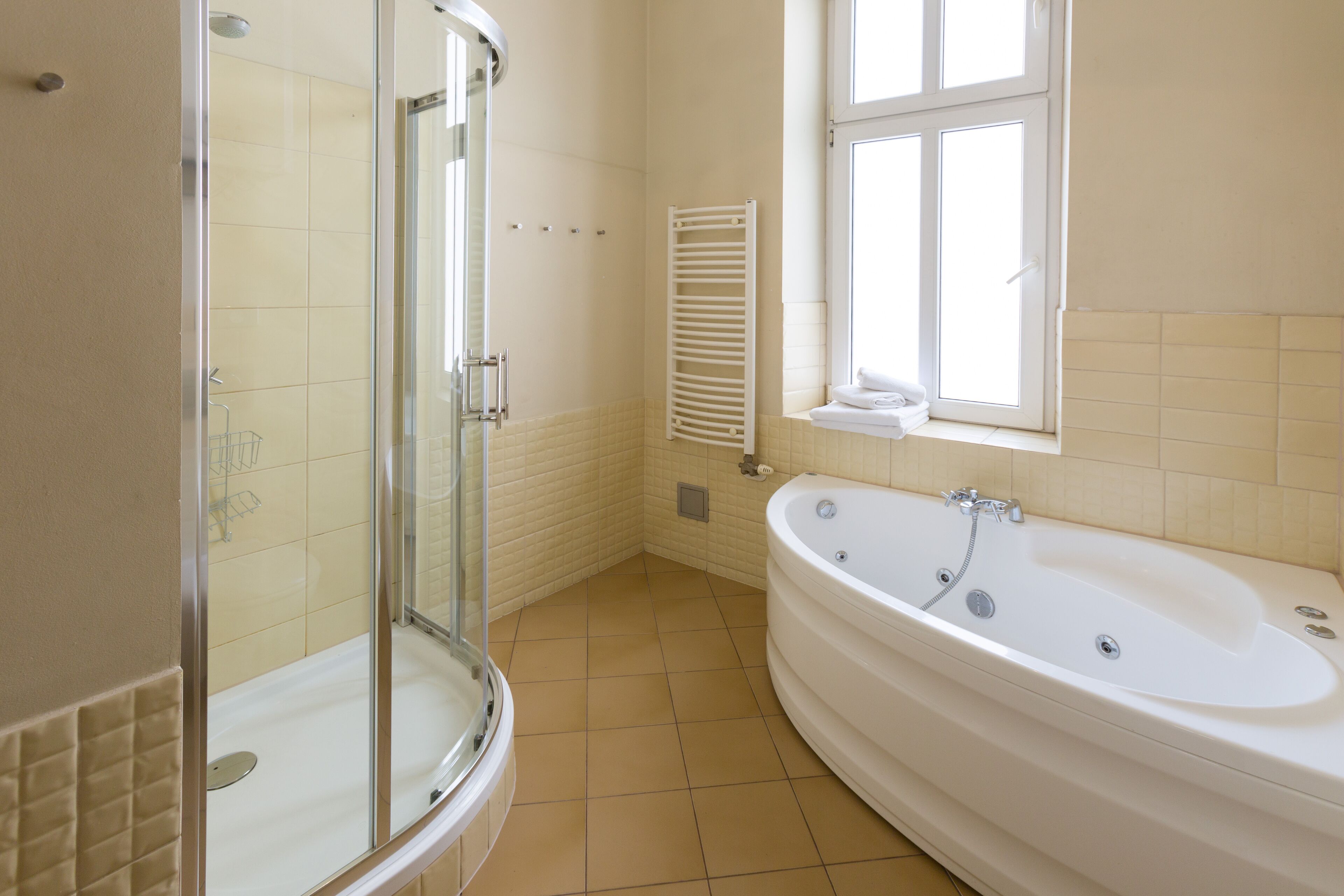 Une salle de bain avec une douche à parois de verre, une baignoire et une fenêtre.
