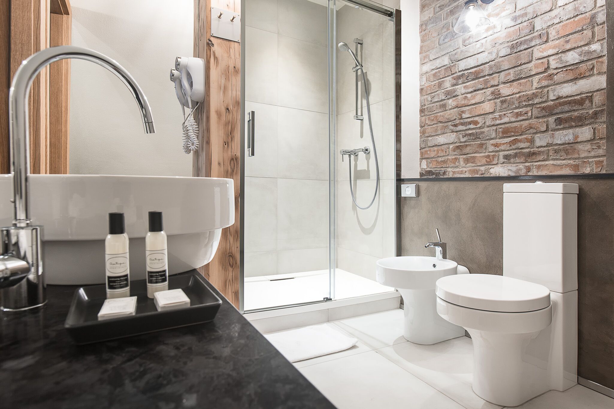 A modern bathroom with a glass-enclosed shower, a large sink, and two toilets.