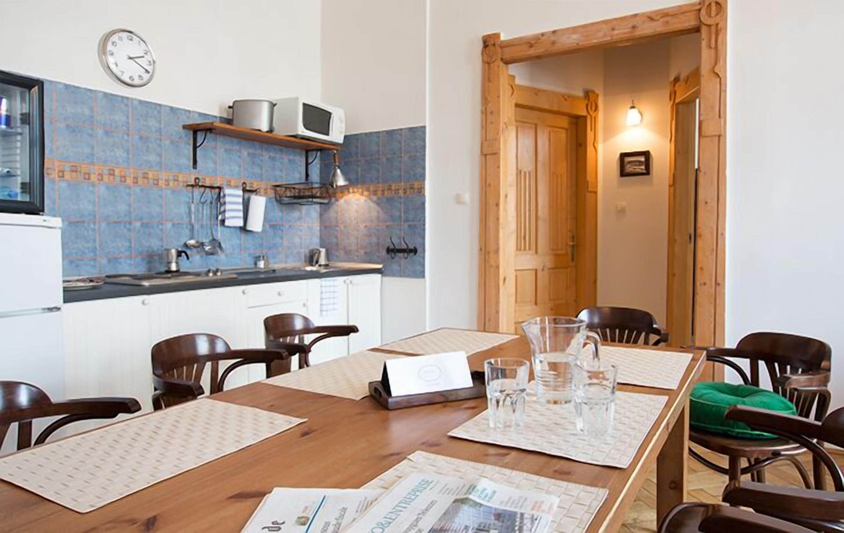 A dining area with a wooden table, chairs, and a kitchen in the background.