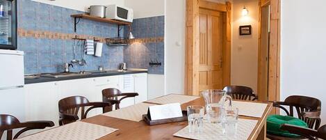 A dining area with a wooden table, chairs, and a kitchen in the background.
