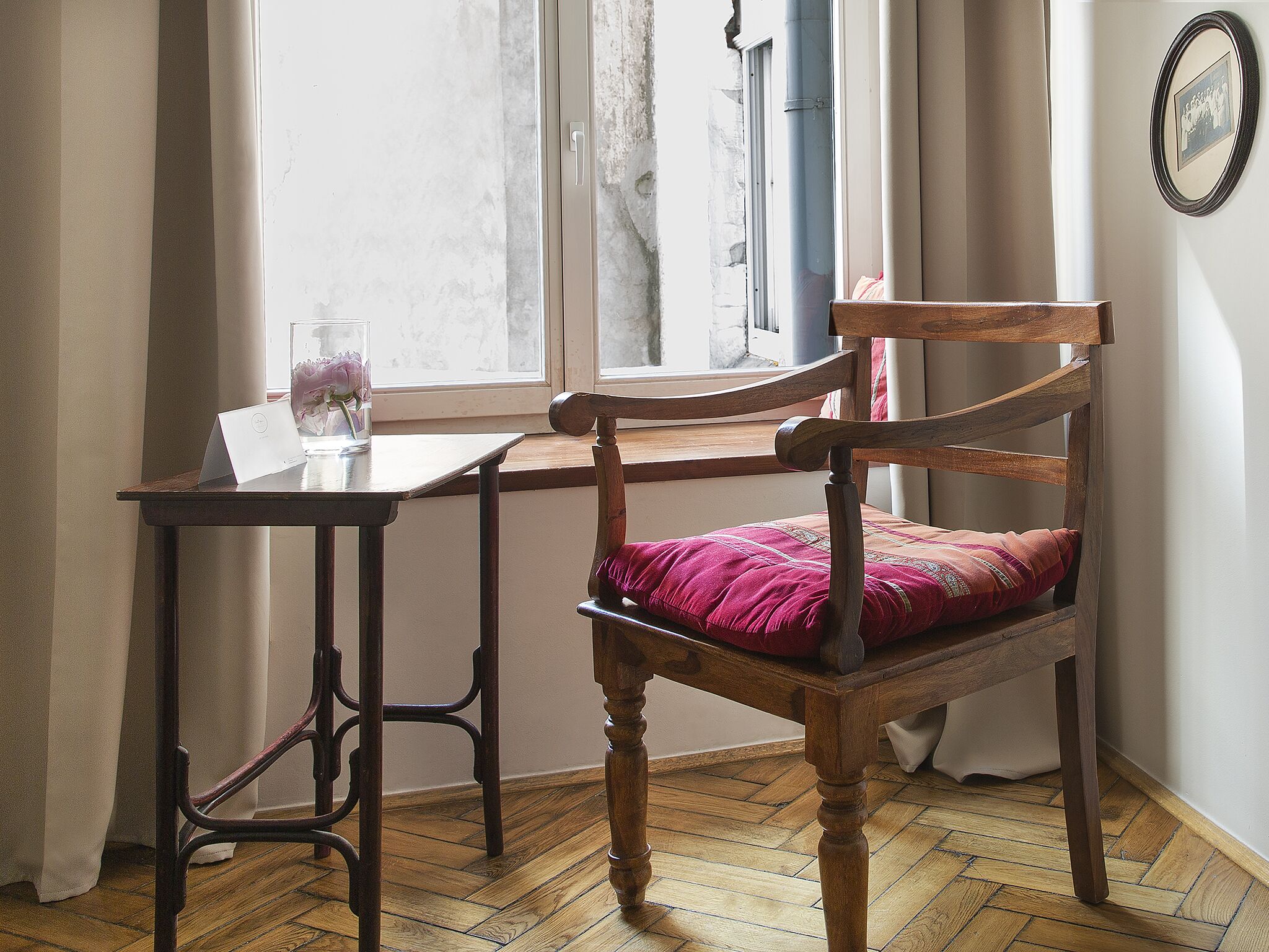 A wooden chair with a red cushion, a wooden table, and a window with curtains.