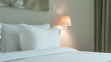 A hotel room with a bed, a wall-mounted lamp, and a painting.