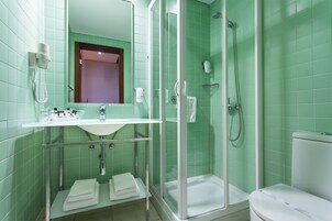 A bathroom with a glass-enclosed shower, a sink with a mirror above it, and a toilet.