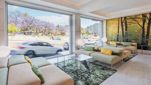 A modern living room with large windows, a city view, and a forest mural on the wall. - HF Fénix Garden (Lisbon)