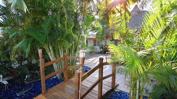 A wooden bridge over a decorative water feature surrounded by lush tropical plants. - Casitas Coral Ridge (Fort Lauderdale)