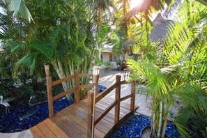 A wooden bridge over a decorative water feature surrounded by lush tropical plants. - Casitas Coral Ridge (Fort Lauderdale)