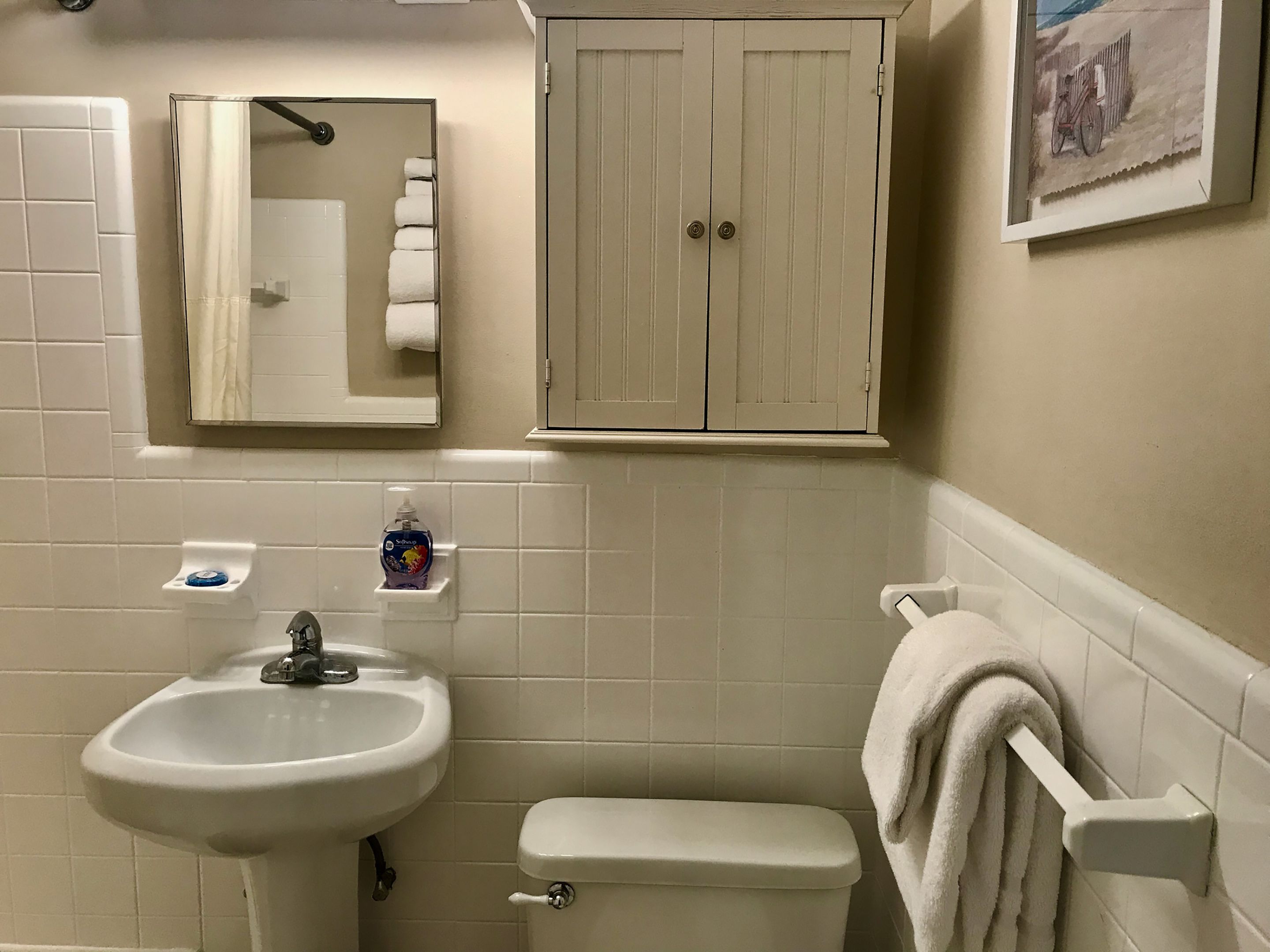 Et badeværelse med vask, toilet og skab.