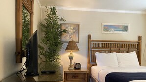 A hotel room with a bed, a bedside table with a lamp, a television, and a potted plant. - Casitas Coral Ridge (Fort Lauderdale)