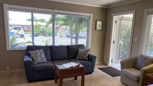 A living room with a dark grey sofa, a wooden coffee table, and a light grey armchair. - Casitas Coral Ridge (Fort Lauderdale)