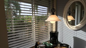 A room with a window with blinds, a coffee maker, a telephone, and a table with papers and a remote control. - Casitas Coral Ridge (Fort Lauderdale)