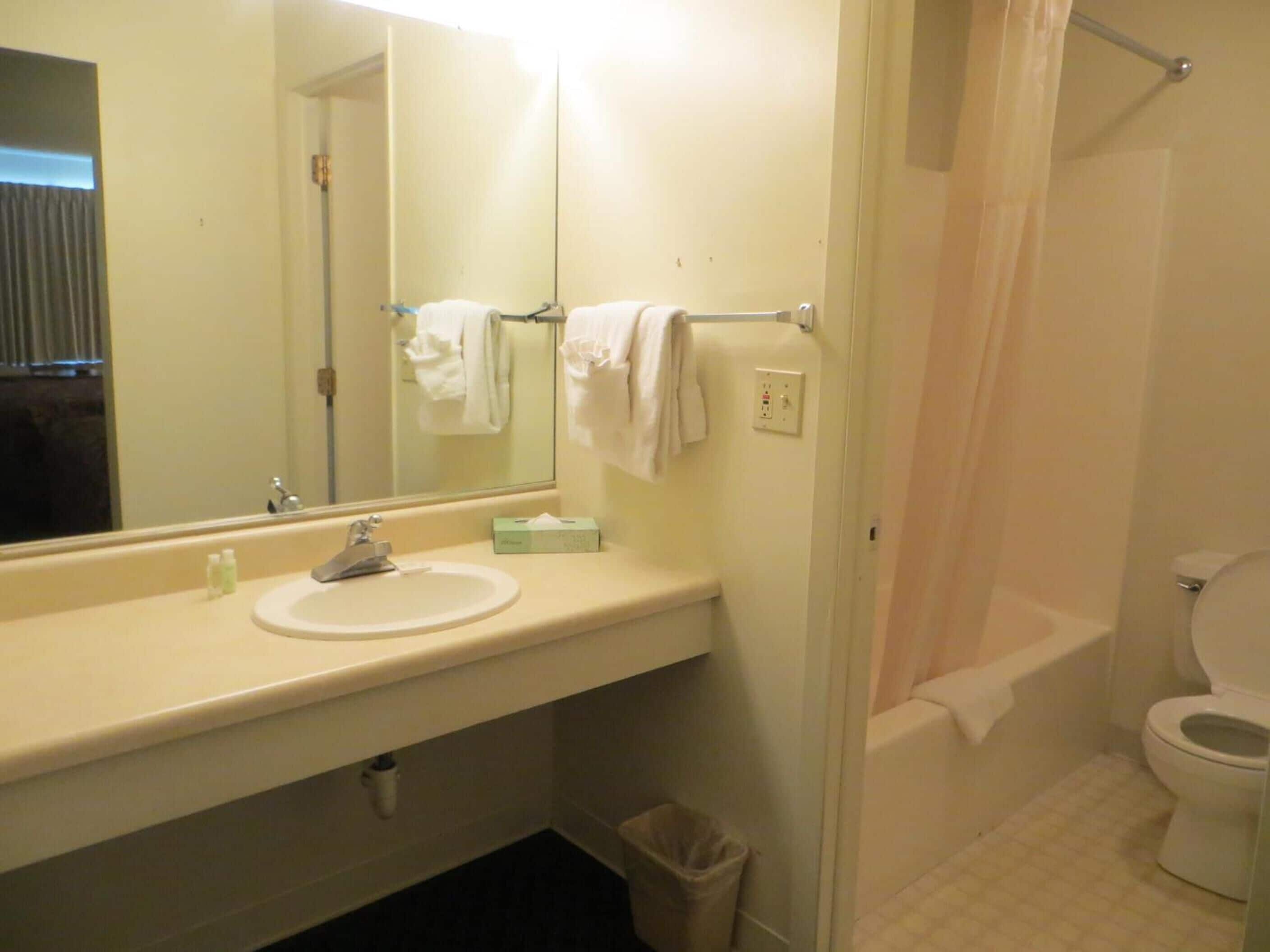 A bathroom with a sink, mirror, towel rack, and toilet.