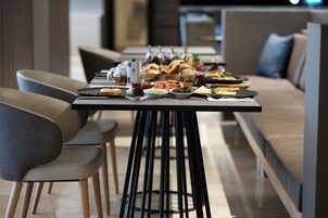 Un comedor con una larga mesa dispuesta para una comida, rodeada de sillas modernas y un sofá.