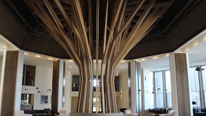 Un vestíbulo moderno con una instalación artística central, zonas de estar y amplios ventanales que aportan luz natural.