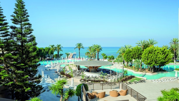 Un resort con zona de piscina, sillones de descanso y vista al océano.