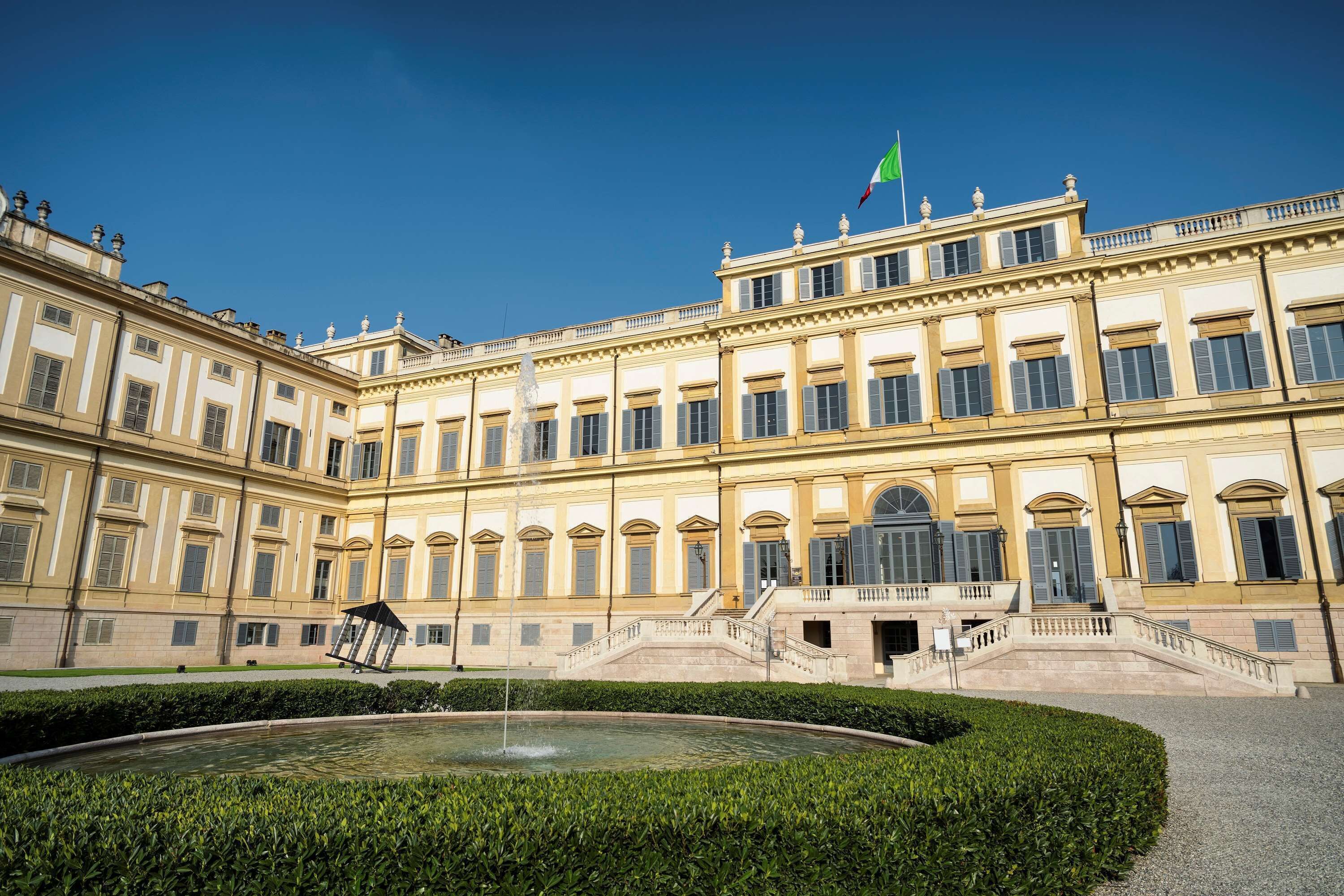 Ein großes, klassizistisches Gebäude mit einer symmetrischen Fassade, zahlreichen Fenstern und einer zentralen Treppe, die zu einem Eingang führt.