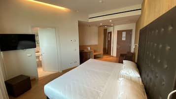 Une chambre d’hôtel moderne dotée d’un grand lit, d’un téléviseur à écran plat fixé au mur et d’un coin salon séparé avec une table et des chaises.