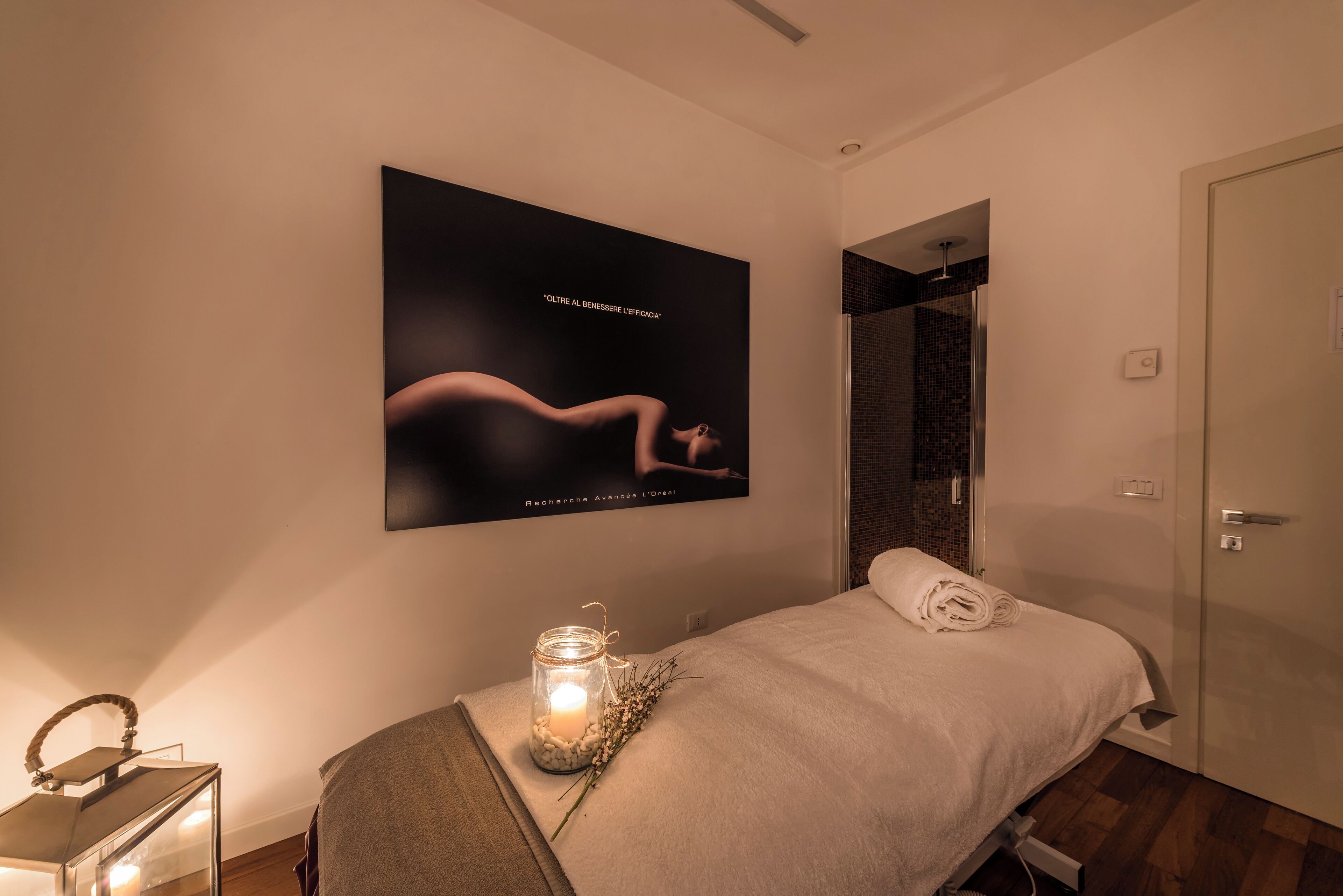 Un dormitorio moderno con cama, mesita de noche con lámpara, un cartel en la pared y un área de ducha.
